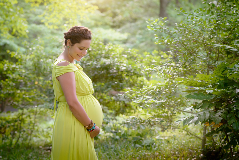 pregnant woman in yellow dress standing in woods